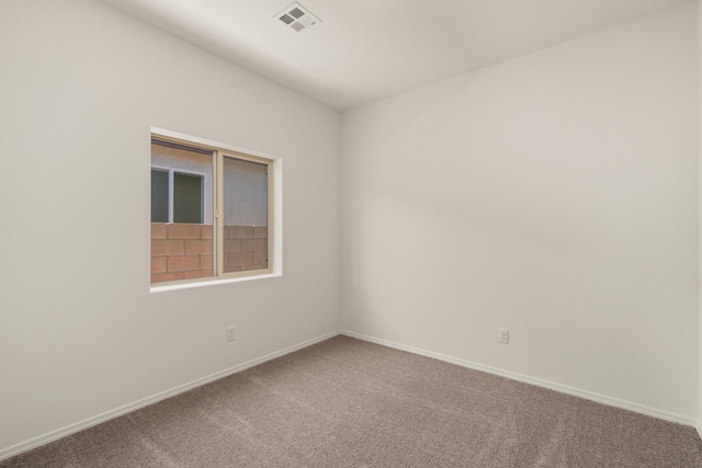 carpeted spare room featuring visible vents and baseboards