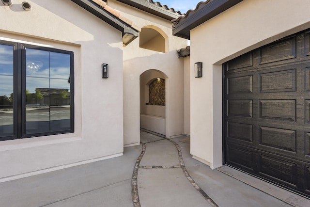 7805 Aguila St NW, Albuquerque, NM 87120 - property entrance with a garage, a tile roof, and stucco siding