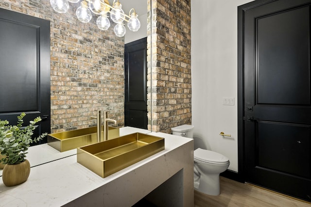 7805 Aguila St NW, Albuquerque, NM 87120 - bathroom featuring wood finished floors, toilet, vanity, and brick wall