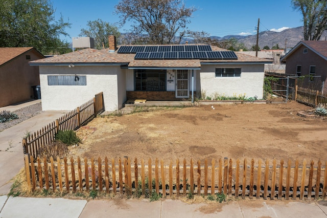 view of front of property with roof mounted solar panels, a fenced backyard, and a mountain view