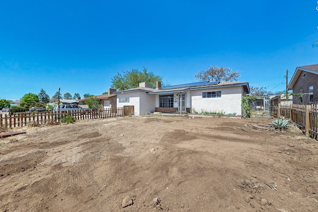view of front of home with a fenced backyard, solar panels, and stucco siding