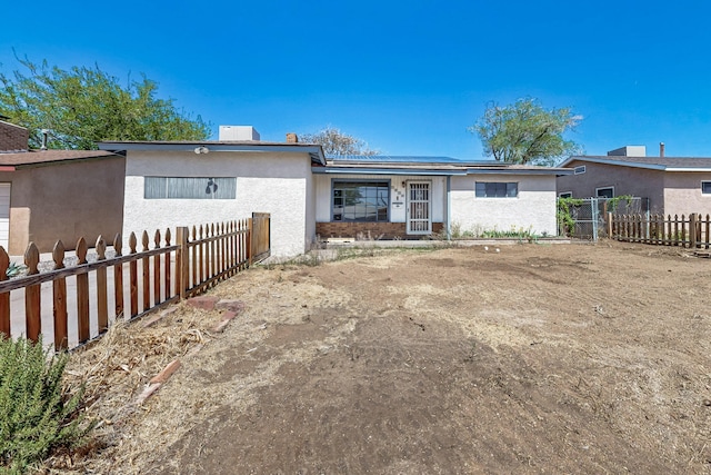 back of property with roof mounted solar panels, fence private yard, and stucco siding