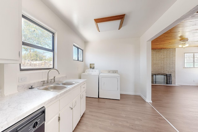 clothes washing area with light wood-type flooring, washer and dryer, a sink, and a wealth of natural light