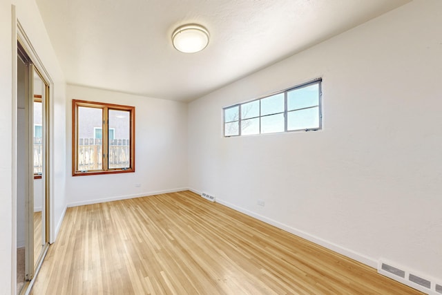 unfurnished room featuring baseboards, visible vents, and light wood-style flooring
