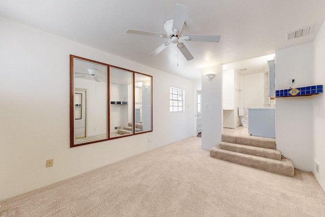 interior space featuring visible vents, carpet flooring, stairs, and ceiling fan