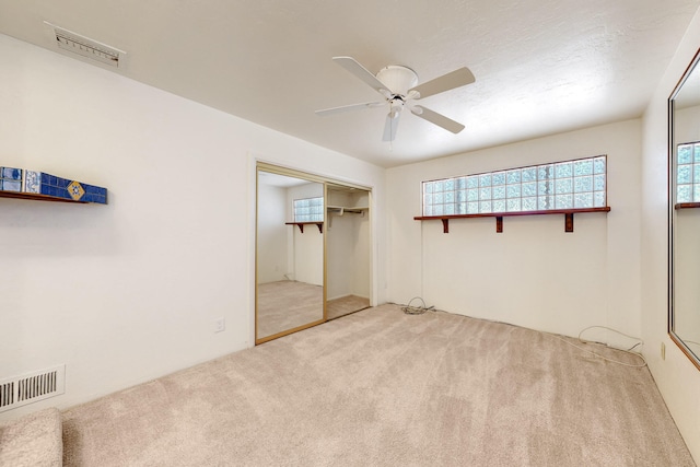 unfurnished bedroom featuring light colored carpet, ceiling fan, visible vents, and a closet