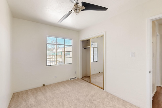 unfurnished bedroom with a ceiling fan, visible vents, carpet floors, and a closet