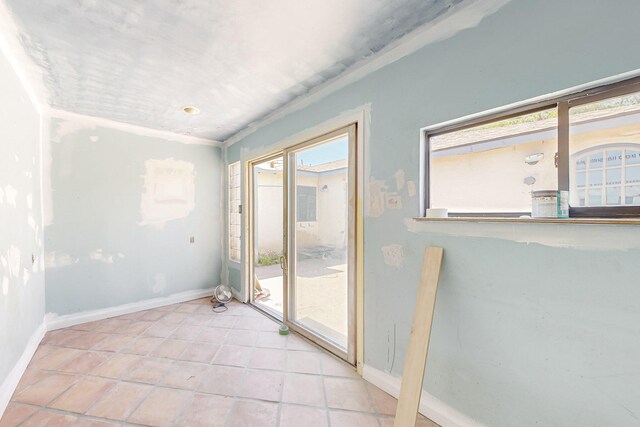 doorway featuring baseboards and light tile patterned floors