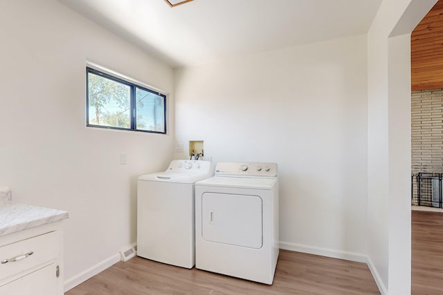 laundry room with cabinet space, light wood-type flooring, baseboards, and washer and clothes dryer