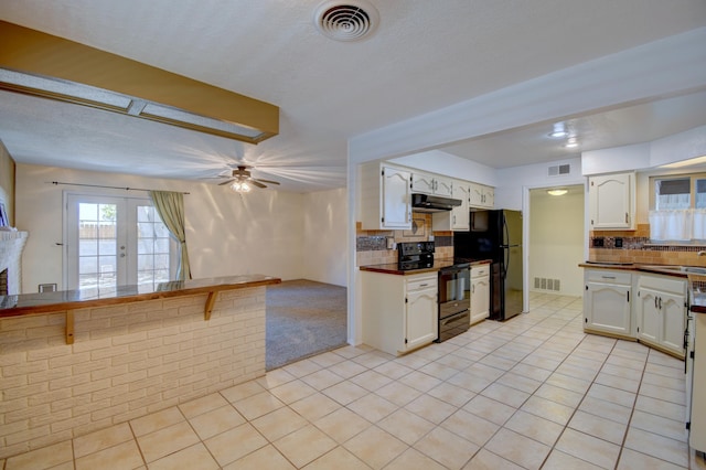 kitchen with black appliances, backsplash, white cabinets, and under cabinet range hood