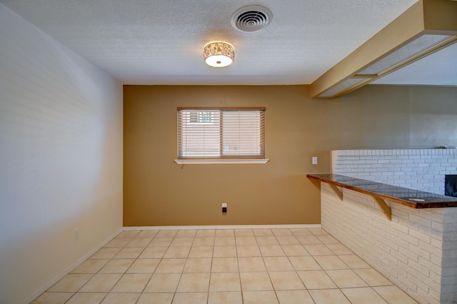 unfurnished room featuring baseboards, visible vents, and a textured ceiling