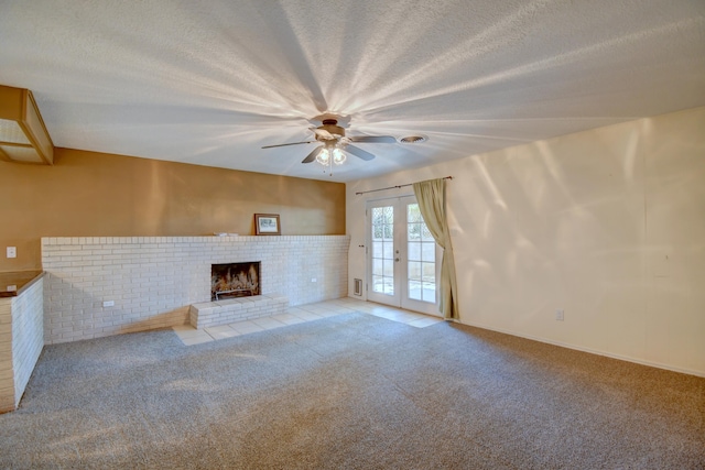unfurnished living room featuring carpet floors, ceiling fan, a brick fireplace, a textured ceiling, and french doors