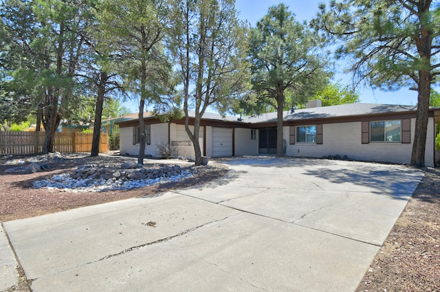 ranch-style home with a garage, a chimney, driveway, brick siding, and fence