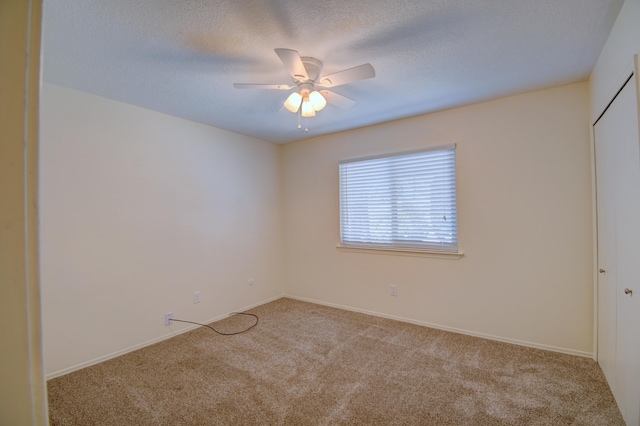 carpeted spare room with a textured ceiling, a ceiling fan, and baseboards