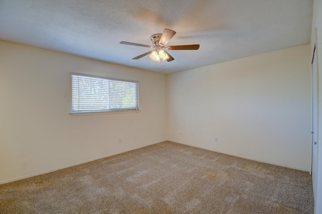 spare room with light colored carpet, a ceiling fan, a textured ceiling, and baseboards
