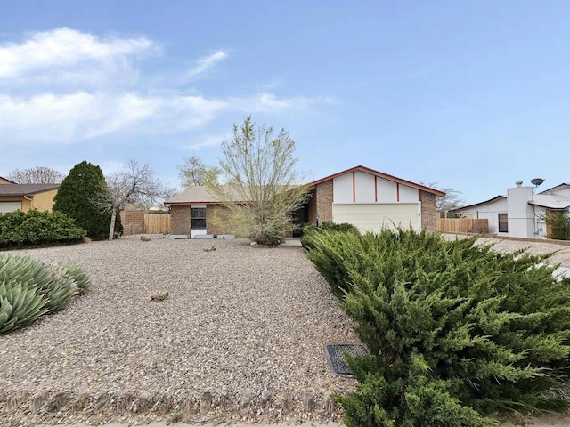 view of front of house with fence, a garage, and brick siding