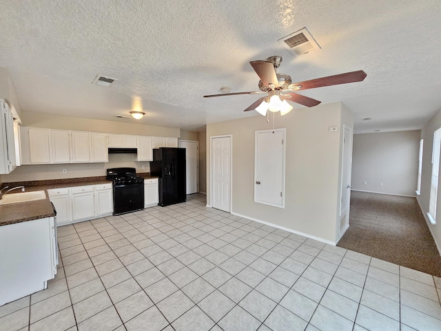 kitchen with a sink, under cabinet range hood, black appliances, dark countertops, and open floor plan
