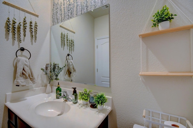 bathroom featuring a textured wall and vanity