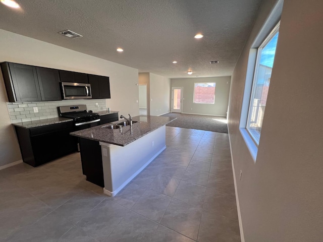 kitchen featuring a sink, stainless steel appliances, visible vents, a textured ceiling, and dark cabinets