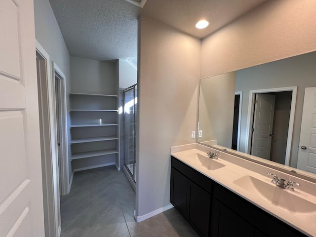 full bathroom with a stall shower, double vanity, and a sink