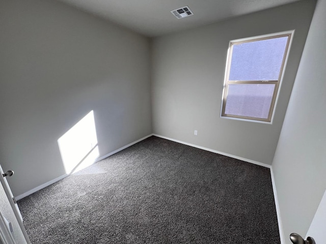unfurnished room with dark colored carpet, visible vents, and baseboards