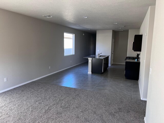 interior space with a textured ceiling, dark tile patterned flooring, baseboards, and a sink