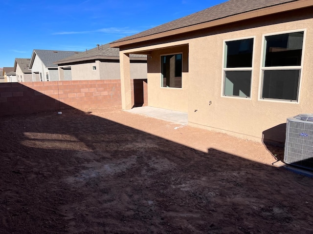back of property featuring central AC, stucco siding, a shingled roof, and fence