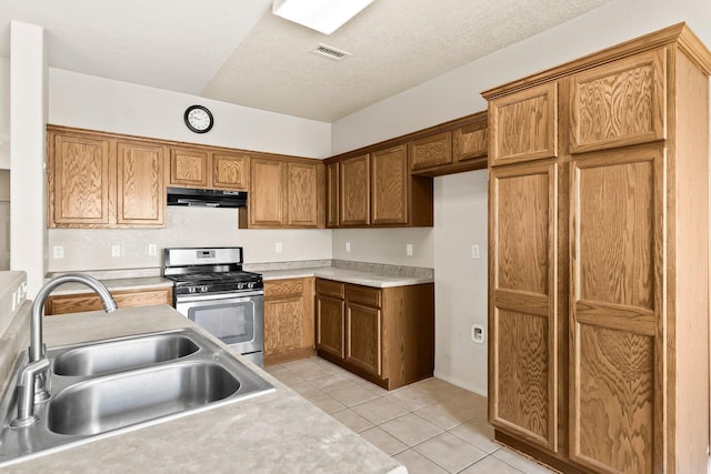 10515 Bilboa St NW, Albuquerque, NM 87114 - kitchen with a sink, under cabinet range hood, light tile patterned flooring, visible vents, and gas stove