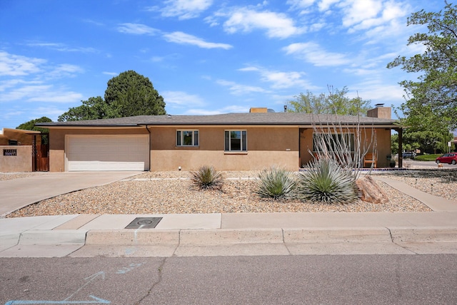 ranch-style house with a garage, a chimney, stucco siding, and driveway
