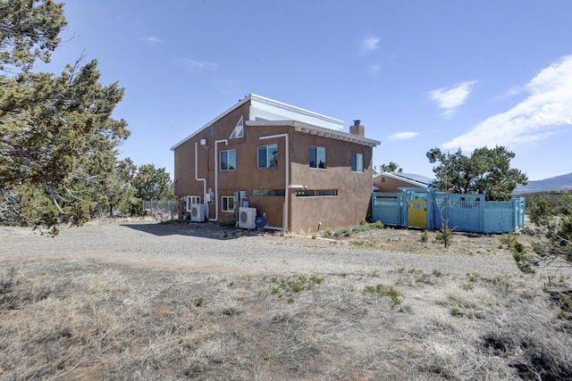 back of house with fence, a gate, ac unit, and a chimney