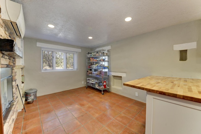 home office with a fireplace, a textured ceiling, a wall unit AC, and recessed lighting
