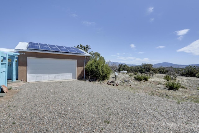 view of side of property featuring a mountain view, solar panels, and stucco siding