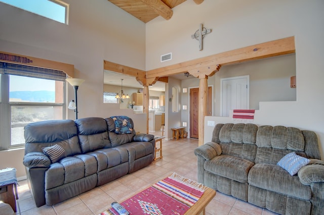 living room with light tile patterned floors, visible vents, a towering ceiling, and beamed ceiling