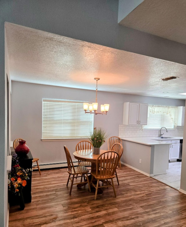 3404 Esplanade Pl SE, Rio Rancho, NM 87124 - dining room with light wood-style floors, baseboard heating, a chandelier, a textured ceiling, and baseboards