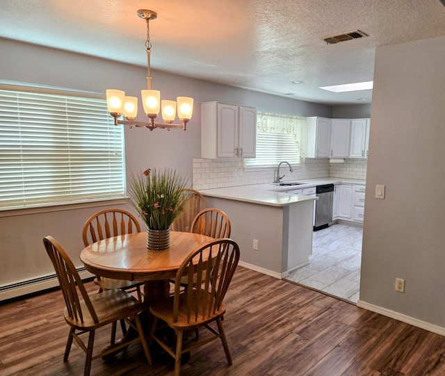 3404 Esplanade Pl SE, Rio Rancho, NM 87124 - dining area with a chandelier, light wood-style flooring, baseboards, a textured ceiling, and a skylight