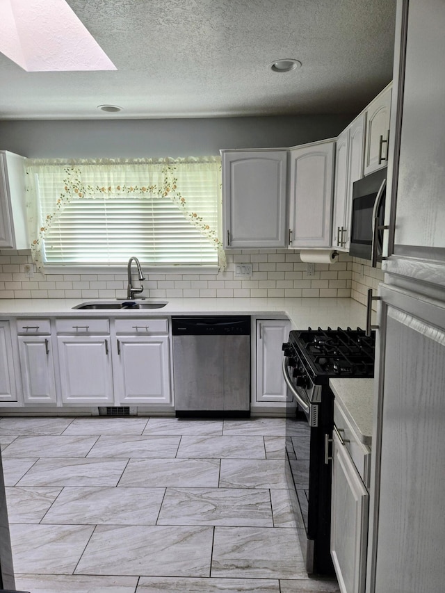 3404 Esplanade Pl SE, Rio Rancho, NM 87124 - kitchen featuring appliances with stainless steel finishes, a sink, backsplash, plenty of natural light, and a textured ceiling