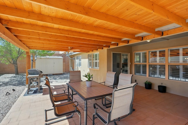 view of patio with outdoor dining area, an outbuilding, a shed, area for grilling, and fence