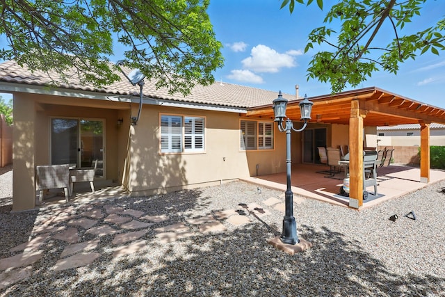 rear view of house featuring a patio, fence, stucco siding, and a tiled roof