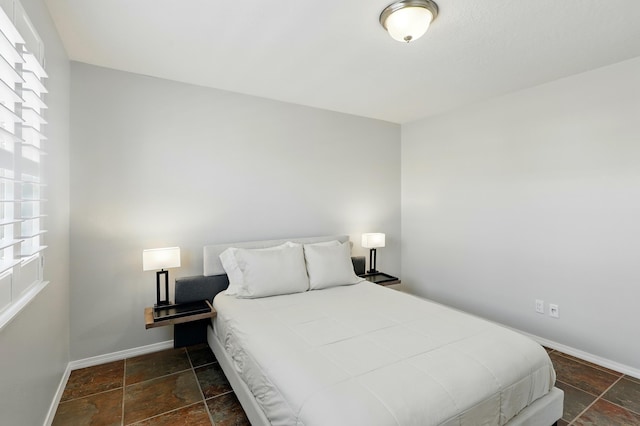 bedroom featuring stone tile floors and baseboards