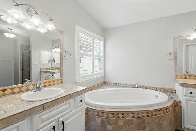 bathroom with a sink, a stall shower, two vanities, vaulted ceiling, and a garden tub