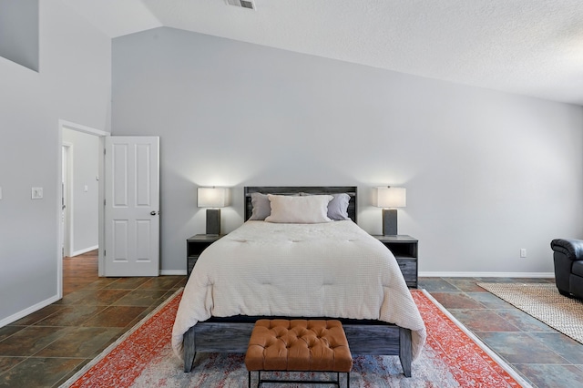 bedroom with stone tile floors, baseboards, visible vents, and high vaulted ceiling