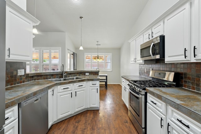 kitchen featuring appliances with stainless steel finishes, white cabinets, a sink, dark wood-style floors, and a peninsula