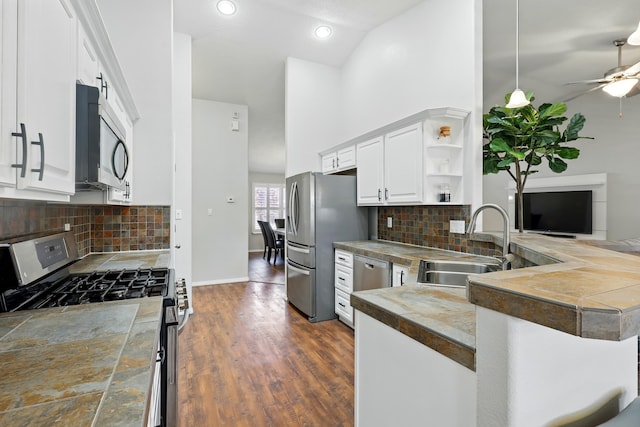 kitchen featuring a sink, stainless steel appliances, high vaulted ceiling, open shelves, and a peninsula