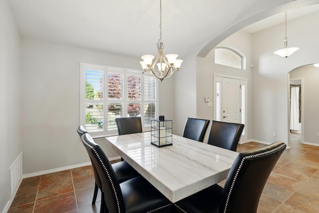 dining area with a chandelier, baseboards, visible vents, and arched walkways