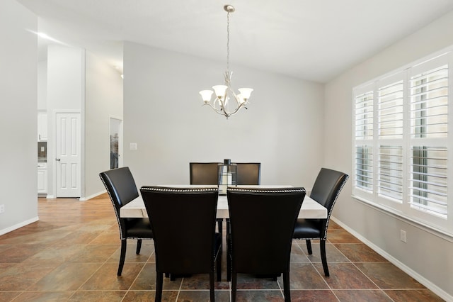 dining area featuring baseboards, a notable chandelier, lofted ceiling, and plenty of natural light