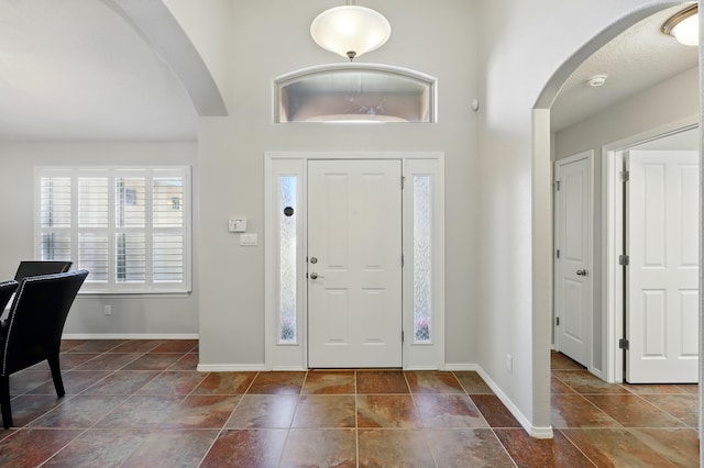 foyer entrance featuring baseboards and arched walkways