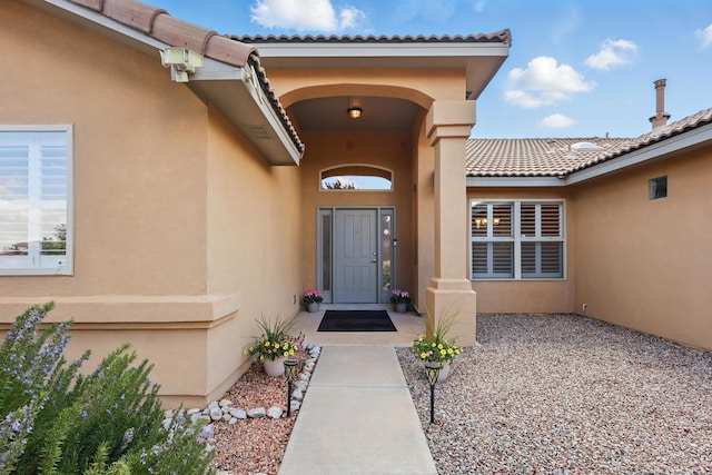 property entrance with stucco siding and a tiled roof
