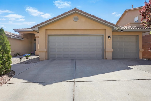 view of front of property featuring a tile roof, concrete driveway, a garage, and stucco siding