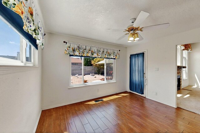 4532 Habershaw Rd NW, Albuquerque, NM 87120 - unfurnished dining area with plenty of natural light, a fireplace, a ceiling fan, wood finished floors, and a textured ceiling
