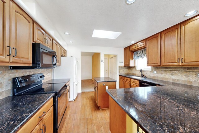 4532 Habershaw Rd NW, Albuquerque, NM 87120 - kitchen with black appliances, a skylight, light wood-style flooring, a sink, and a kitchen island